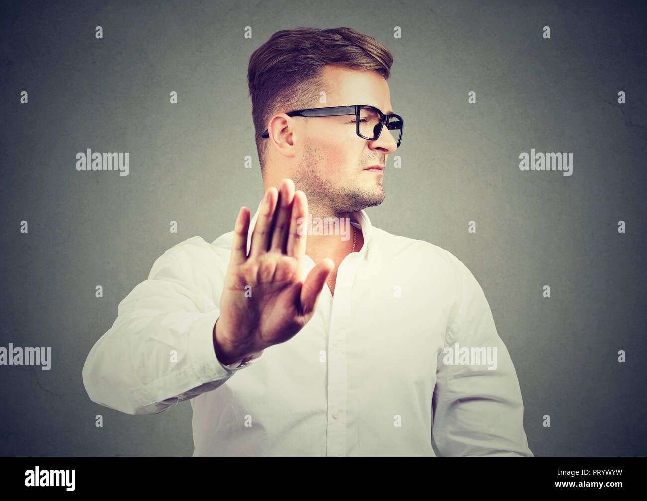 Annoyed angry man with bad attitude giving talk to hand gesture isolated on gray background. Negative human emotion face expression feeling body langu Stock Photo
