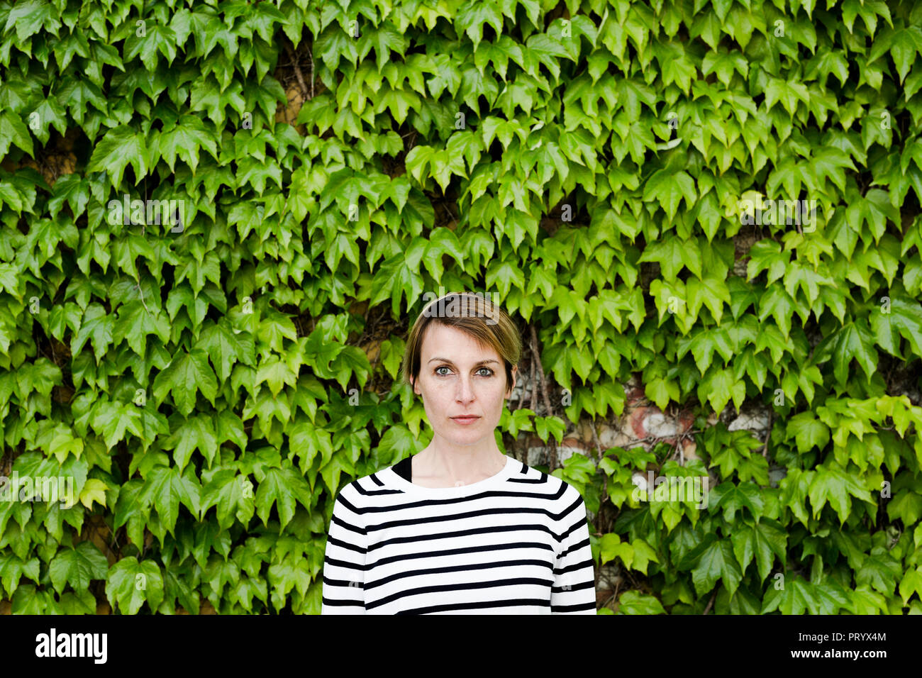 Portrait of woman in front of facade greenery Stock Photo