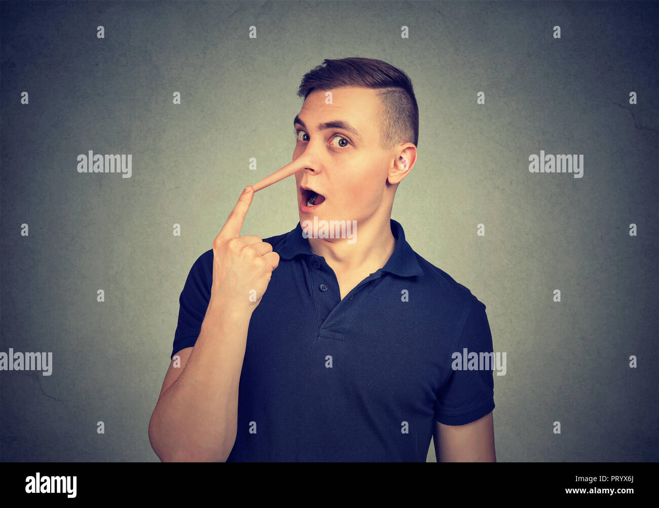Young man looking surprised at camera touching long fake nose of liar on  gray background Stock Photo - Alamy