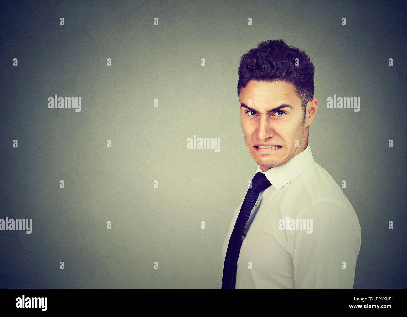 Formal man in shirt with displeased grimace looking grumpy at camera on gray background Stock Photo
