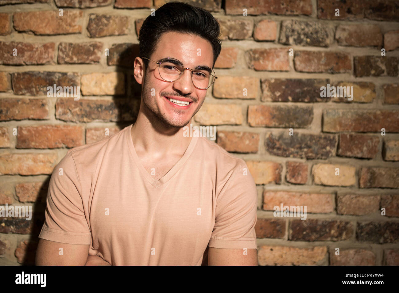 Portrait of smiling young man at brick wall Stock Photo - Alamy