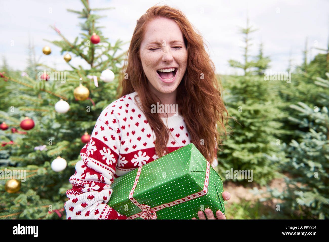 Portrait of redheaded woman with Christmas present crying of joy Stock Photo