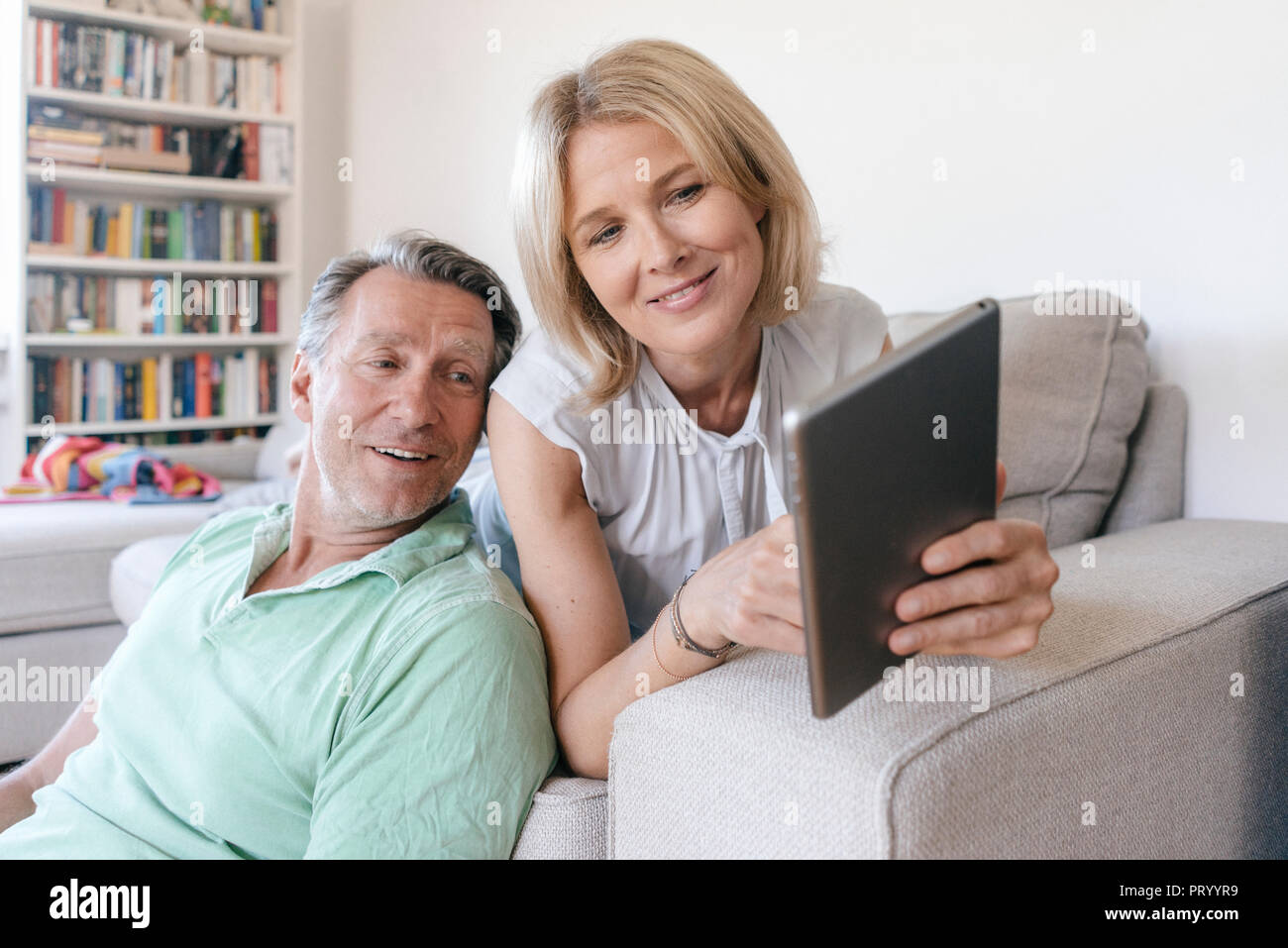 Smiling mature couple at home using tablet Stock Photo