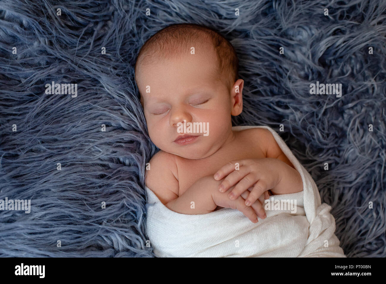 Newborn baby boy in bed. New born child sleeping under a white knitted