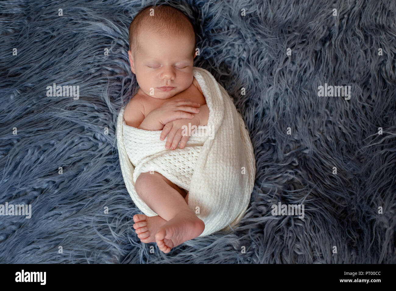 Newborn baby boy in bed. New born child sleeping under a white knitted