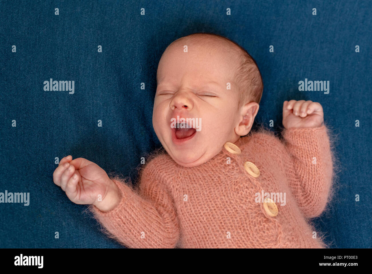 Newborn baby boy 14 days wearing knitted suit sleeping in bed closeup
