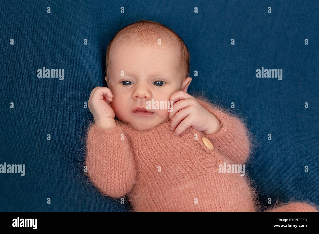 Newborn baby boy 14 days wearing knitted suit sleeping in bed closeup