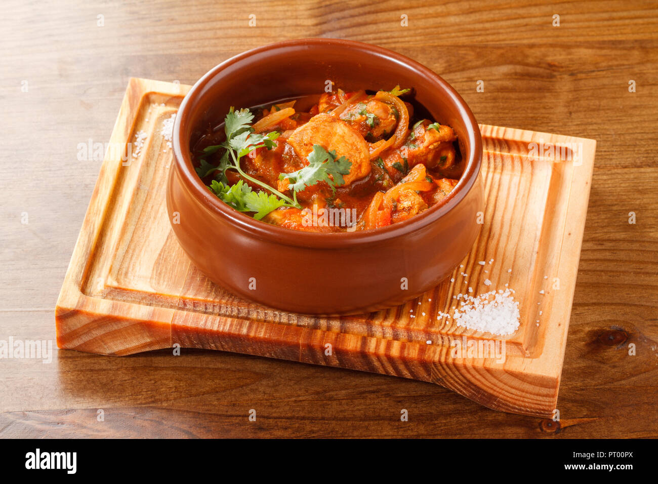 Chicken curry served in a Clay pot/Bowl on a wooden board. Stock Photo