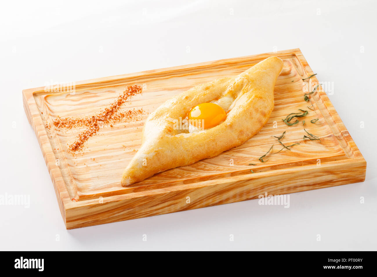 Traditional Armenian Khachapuri on a wooden board (stuffed cheese bread with egg yolk and butter) on white background Stock Photo