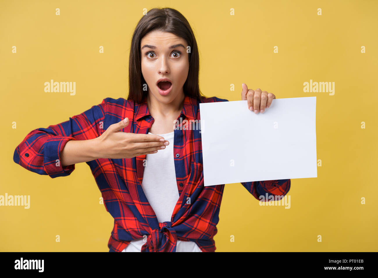 Amazement or surprised female with blank white panel, isolated on yellow background. Stock Photo