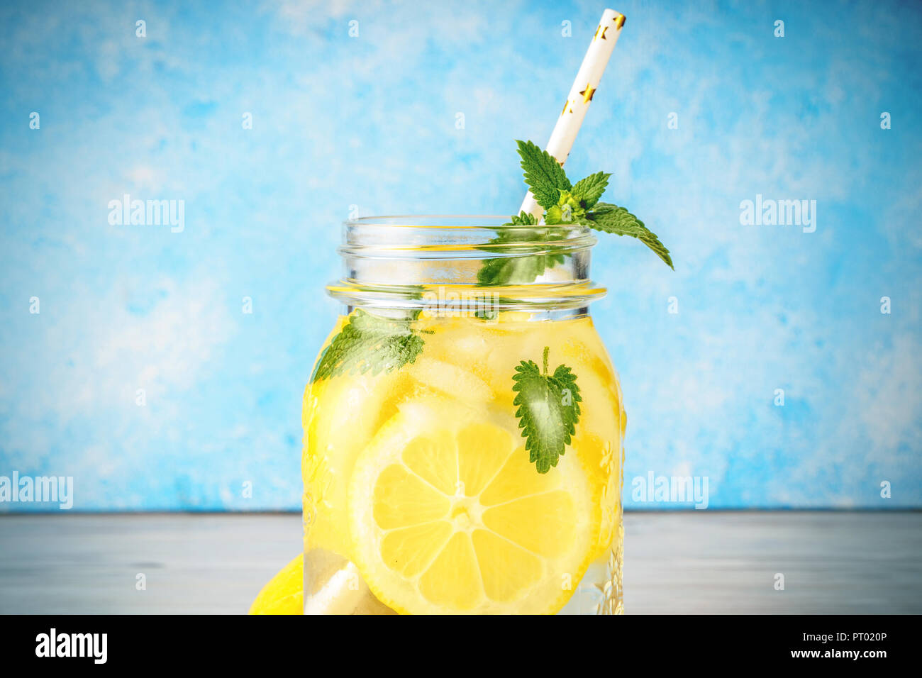 Coctail jar of lemonade and mint leaves on wooden table blue background Natural lemon water homemade food is popular detox beverage Glass of antioxidant infusion. Stock Photo