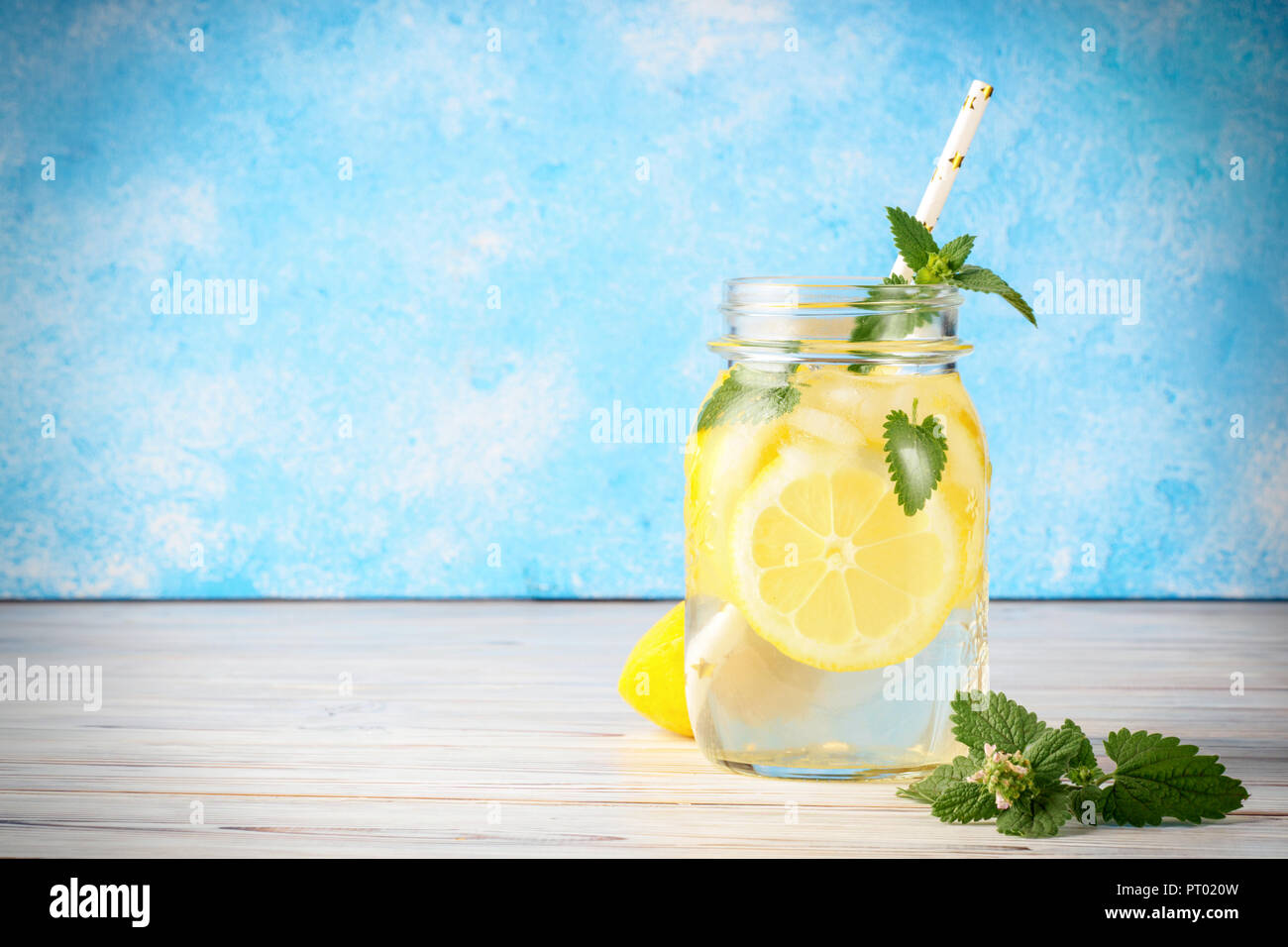 Coctail jar of lemonade and mint leaves on wooden table blue background Natural lemon water homemade food is popular detox beverage Glass of antioxidant infusion Stock Photo