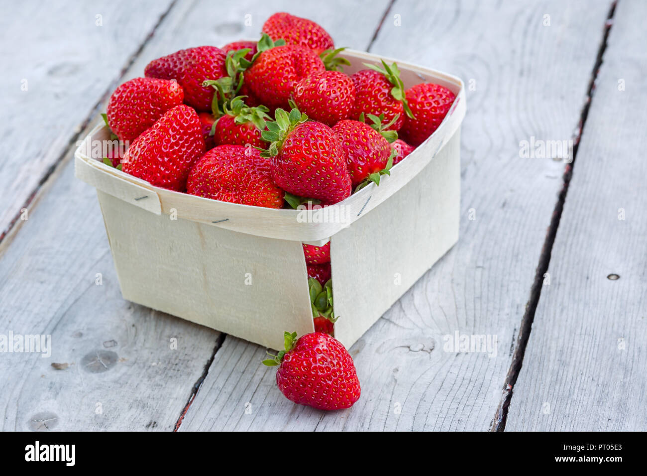 Box of freshly picked ripe red strawberries on a wooden table. Stock Photo