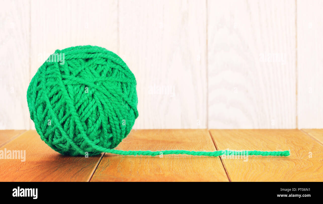 green yarn ball lying on wooden background Stock Photo