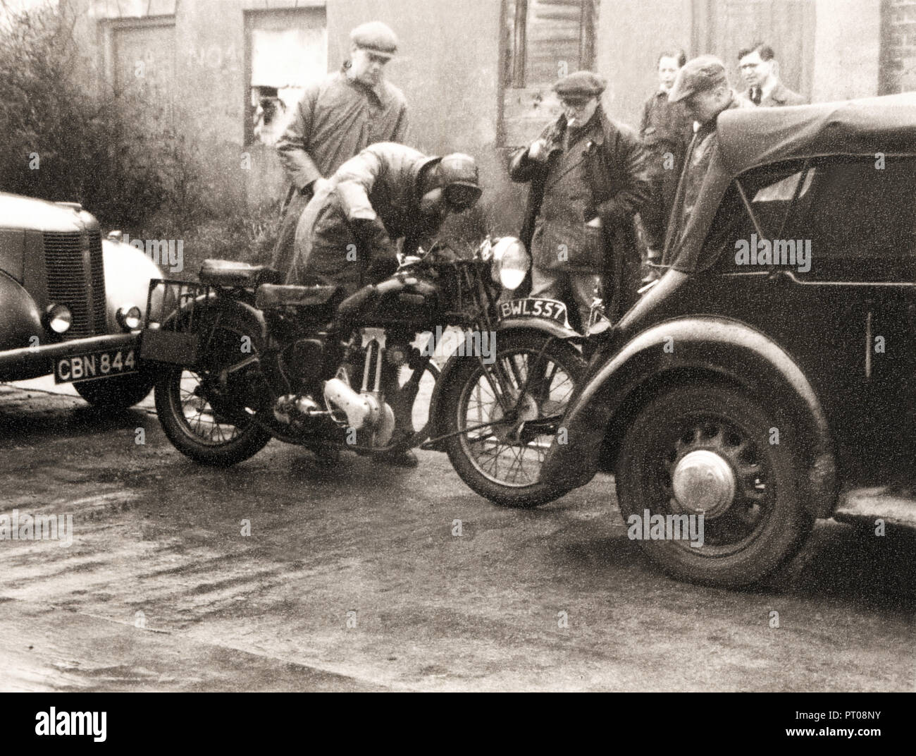 Men in street gathered around a 1934 Ariel Red Hunter motorcycle in the 1930s Stock Photo