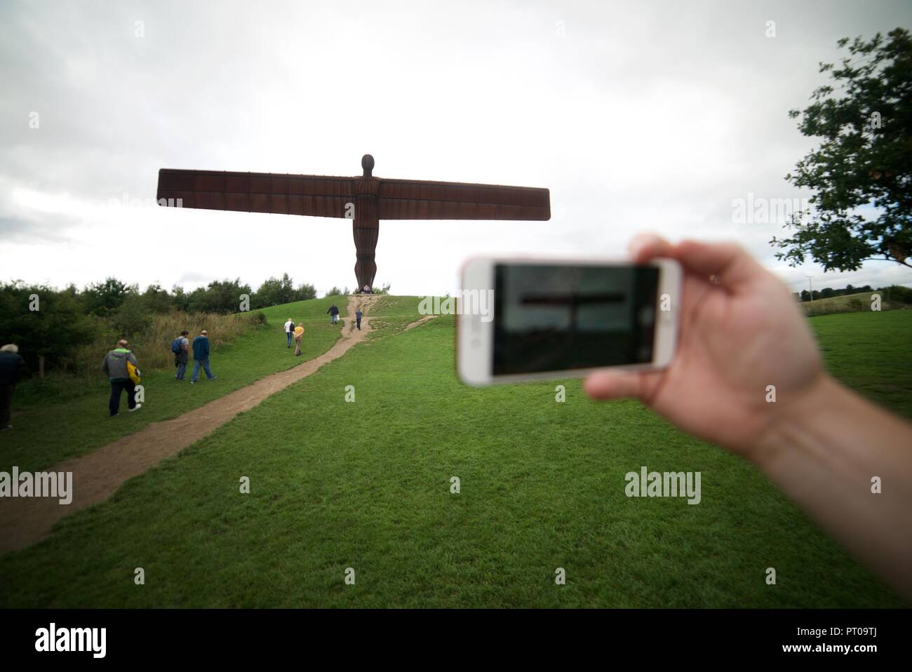 Tourist taking a photo of the Angel of the North statue with their phone, a person photographing the Angel of the North sculpture in Tyne and Wear. Stock Photo