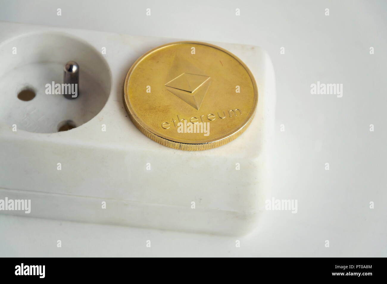 Ethereum coin lying on power strip extension cord with empty socket