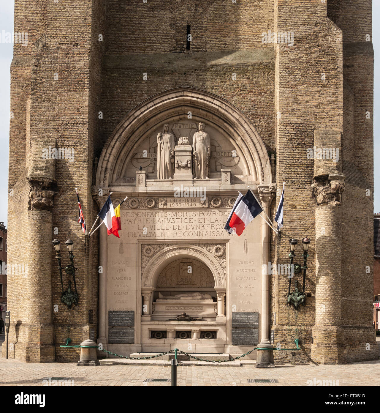 Dunkerque, France - September 16, 2018: Closeup of World wars memorial with flags at base of Belfry of Dunkirk. Fifty shades of brown broken by colors Stock Photo