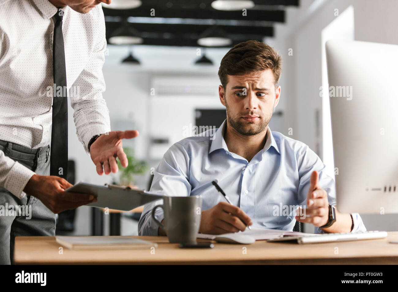 Upset business man having problems with work while sitting by the table in office Stock Photo
