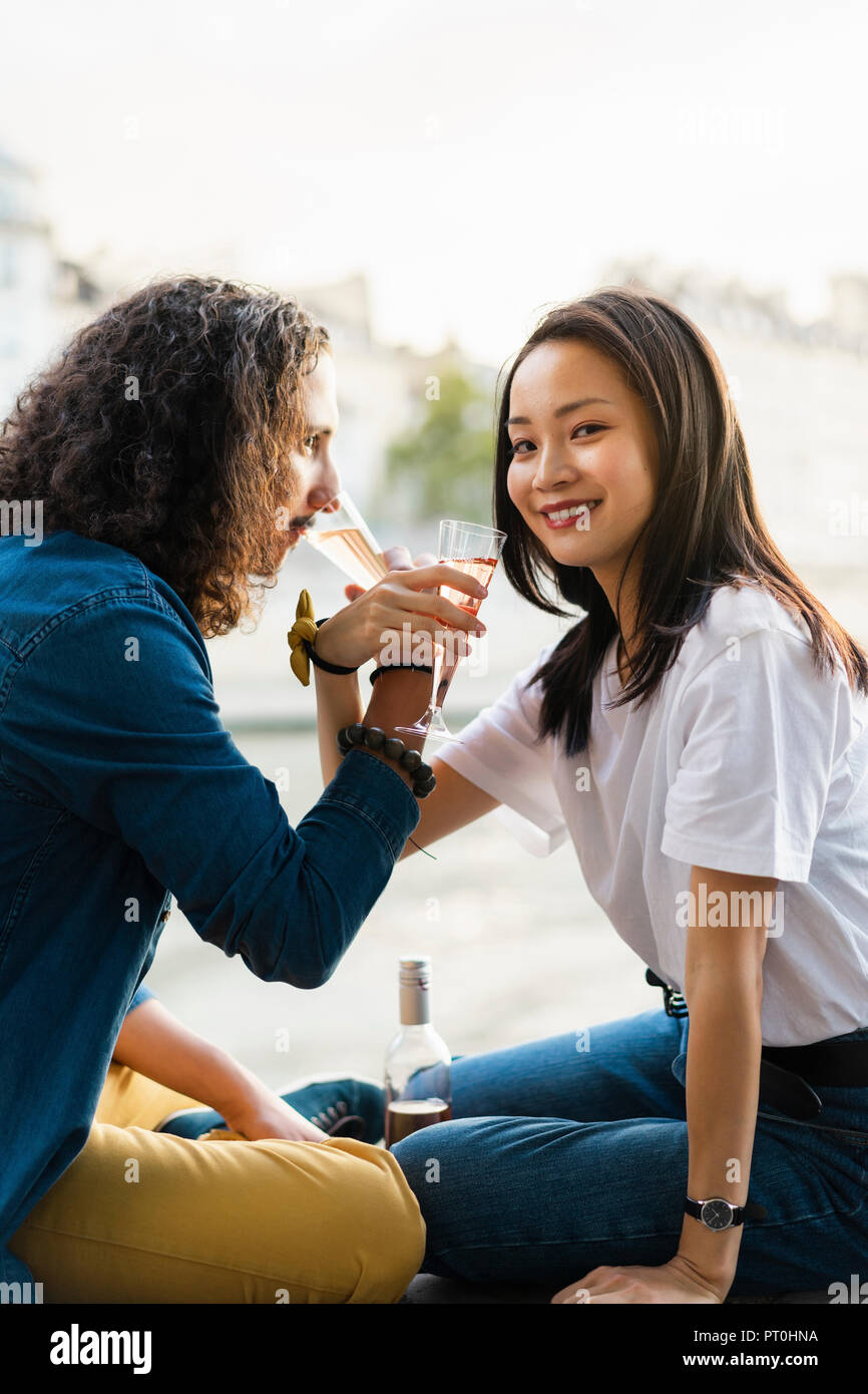 Young couple drinking champagne at the riverside Stock Photo