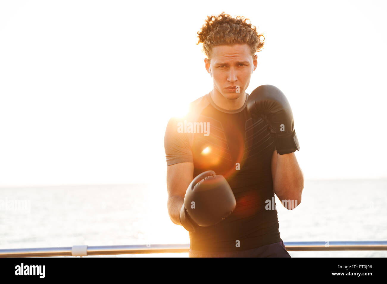 Focused young sportsman in boxing gloves training outdoors Stock Photo