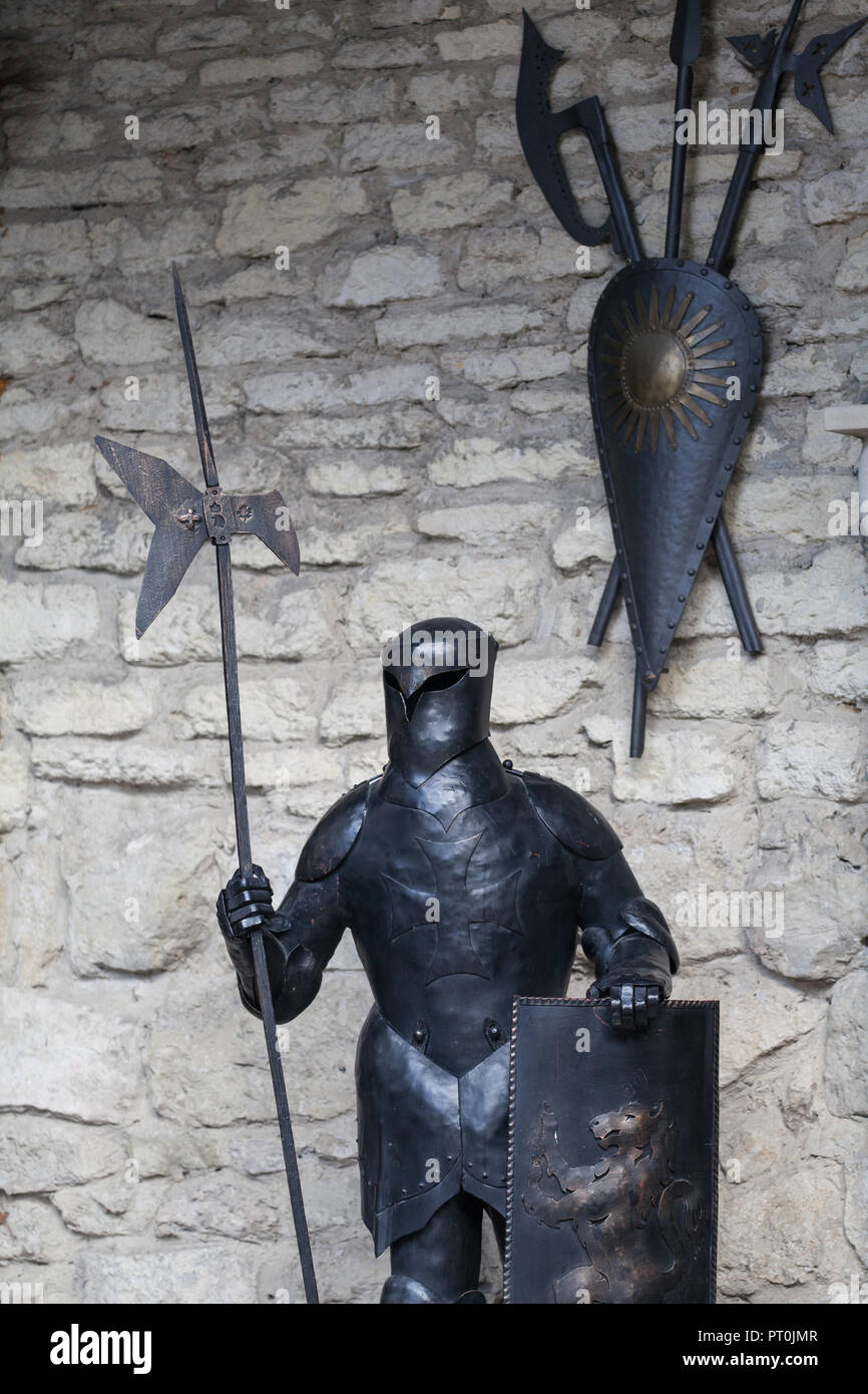 Ukraine, Lviv - October 4, 2018. Knight in full armor with a sword against the background of the ancient walls of a stone castle. Suit of knight armou Stock Photo