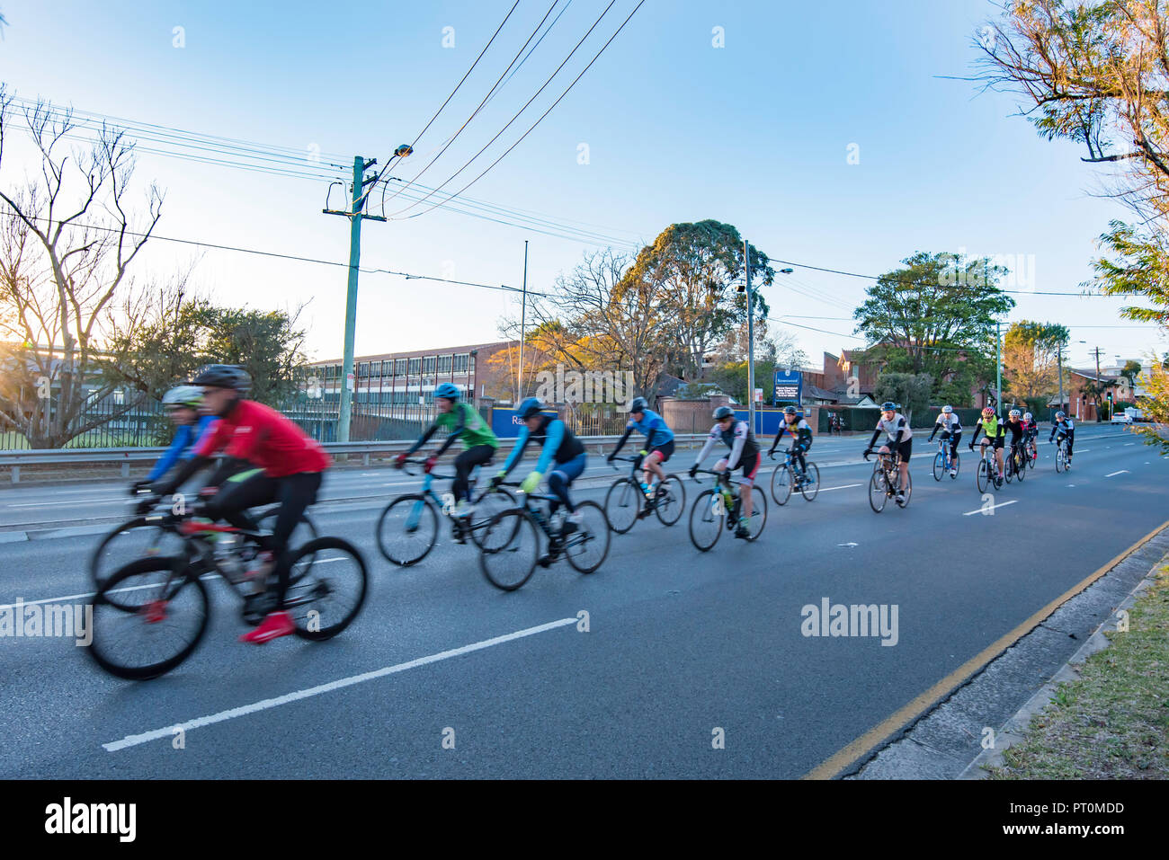 Sunday morning cyclists riding on the Pacific Highway near Gordon, New South Wales just after dawn Stock Photo
