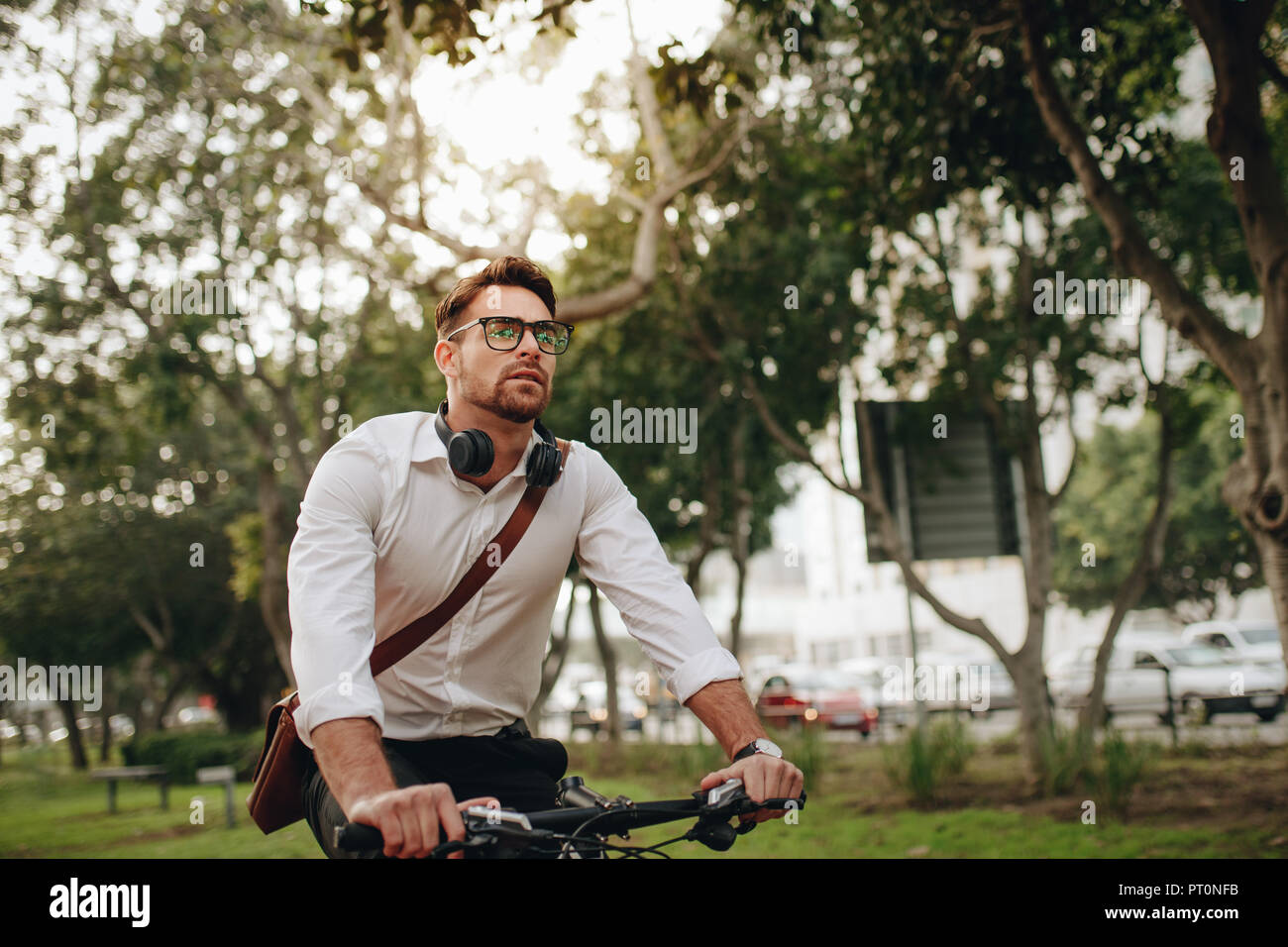 Health conscious man commuting to office on a bike. Man wearing office bag riding a bicycle. Stock Photo