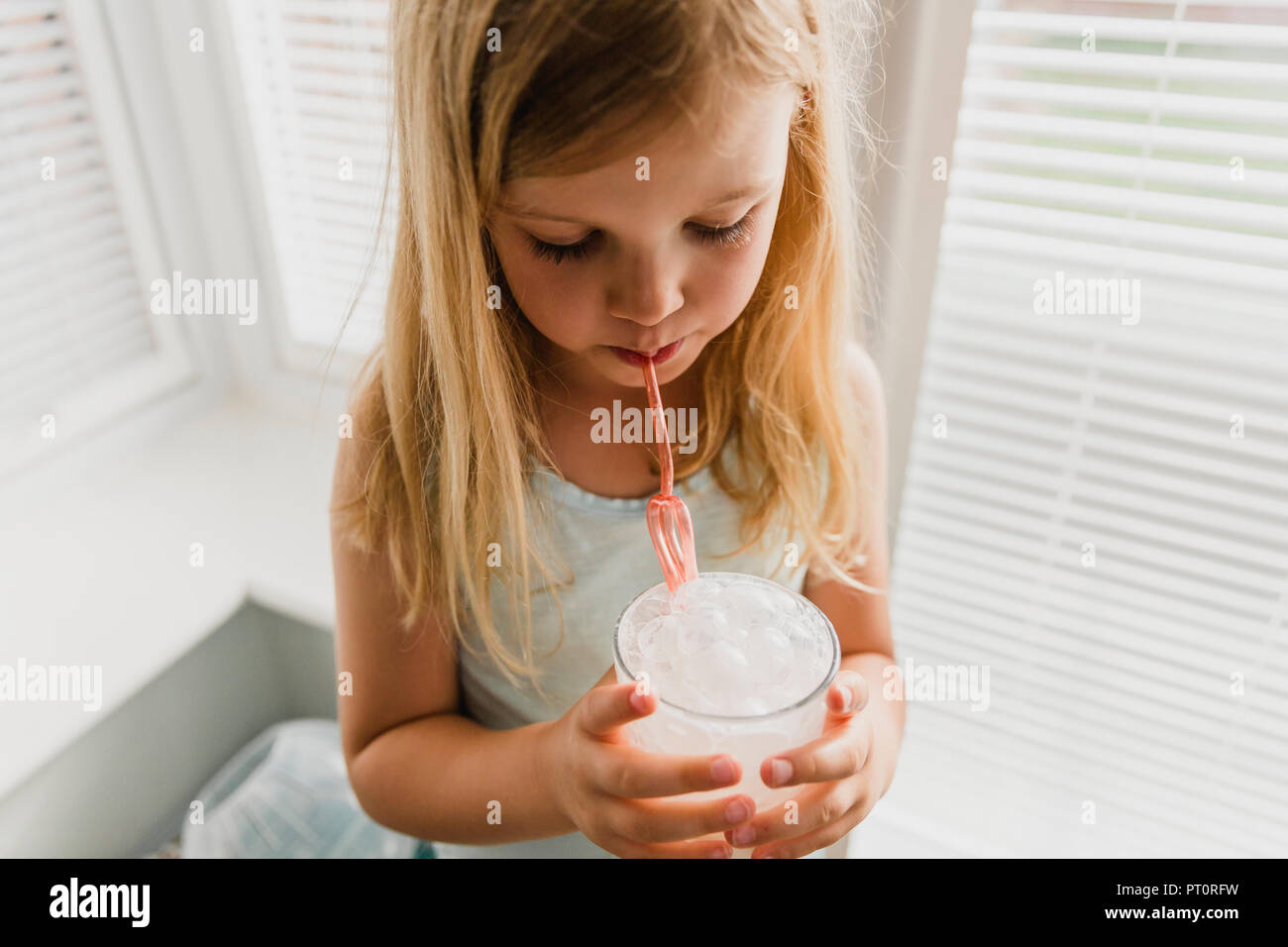 Blond little girl blowing milk bubbles Stock Photo
