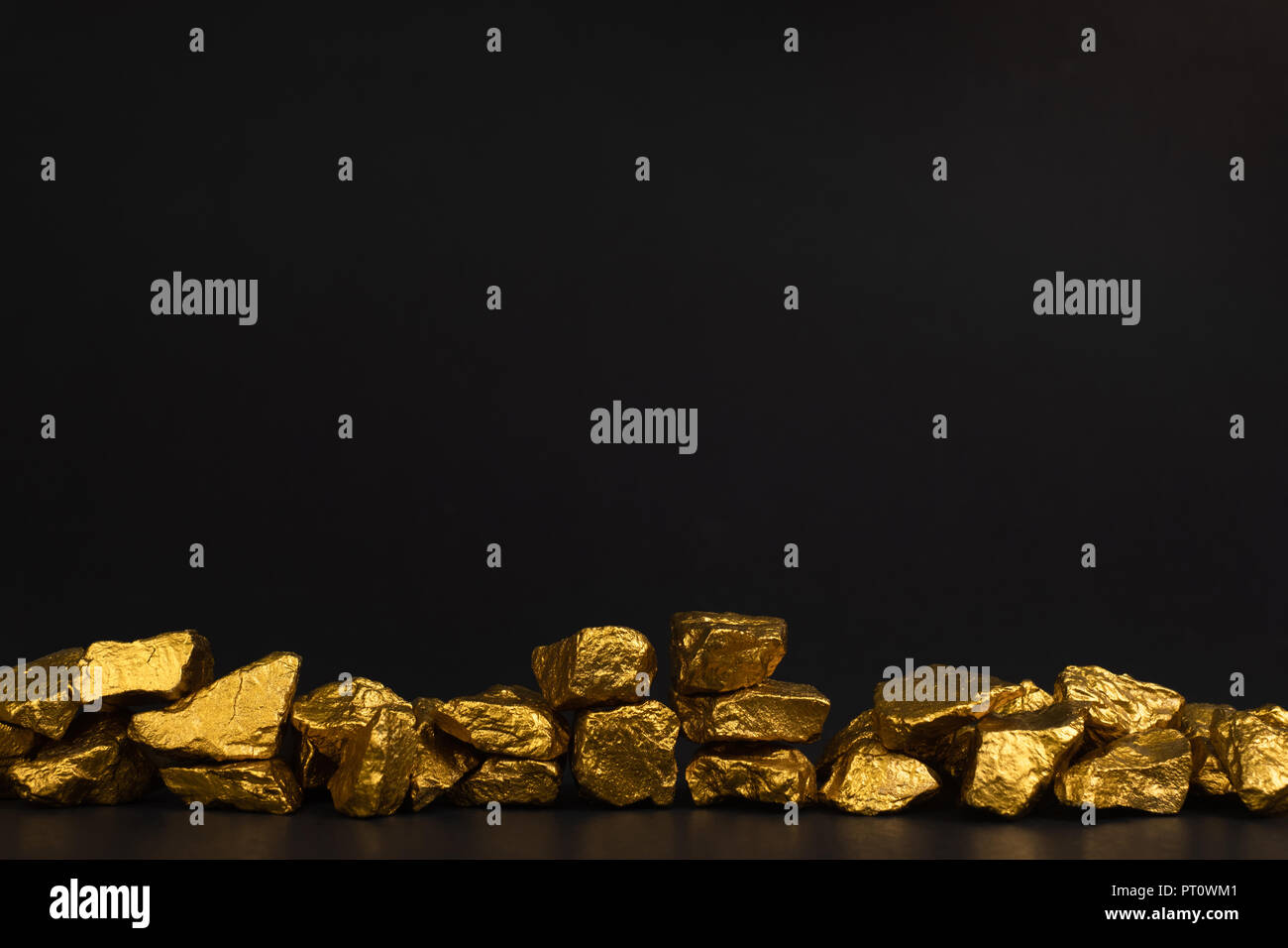 A pile of gold nuggets or gold ore on black background, precious stone or lump of golden stone, financial and business concept idea. Stock Photo