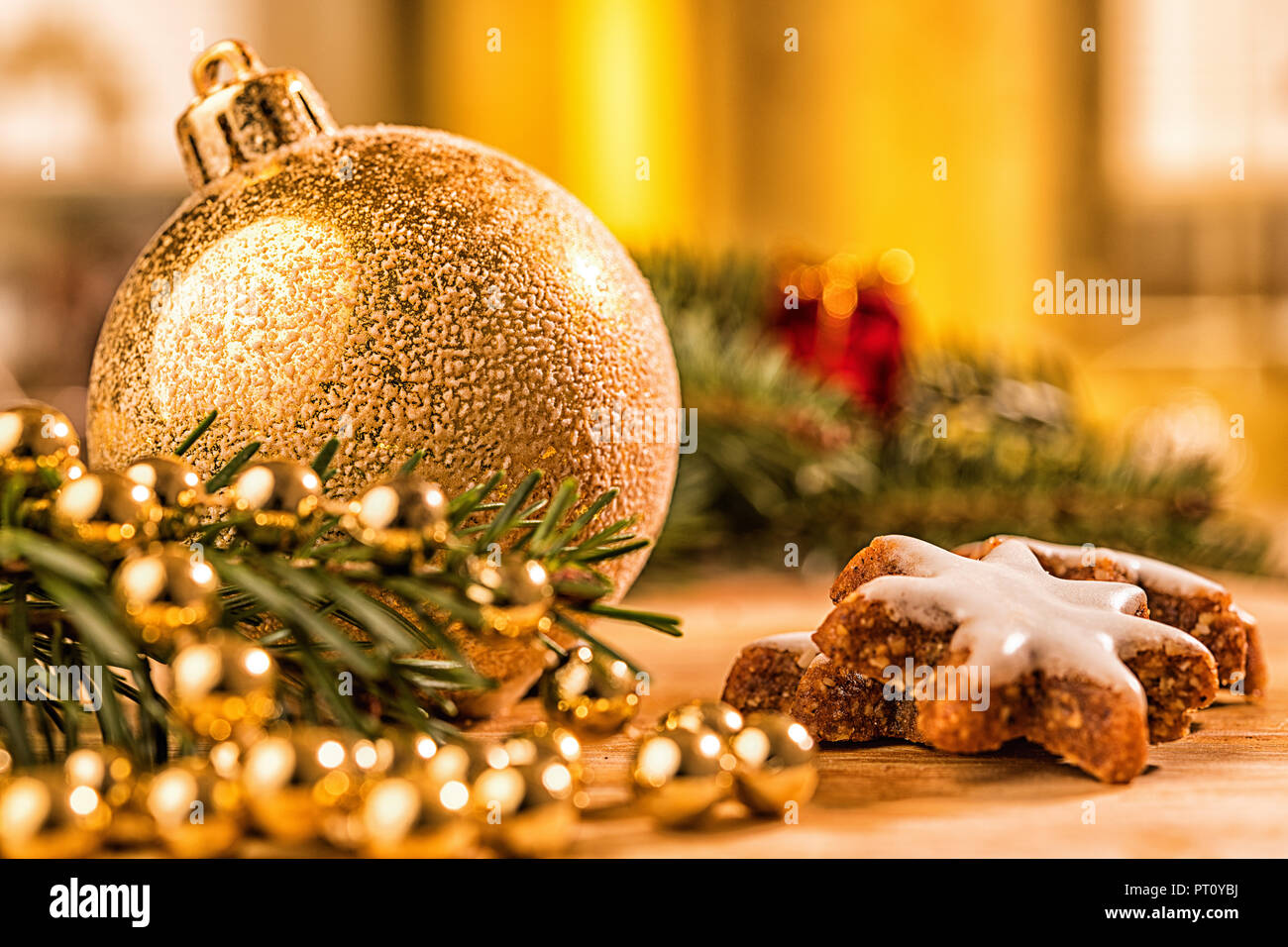 Goldene christbaumkugel mit Tannenzweig, Kerze,  Lichter und Deko Stock Photo
