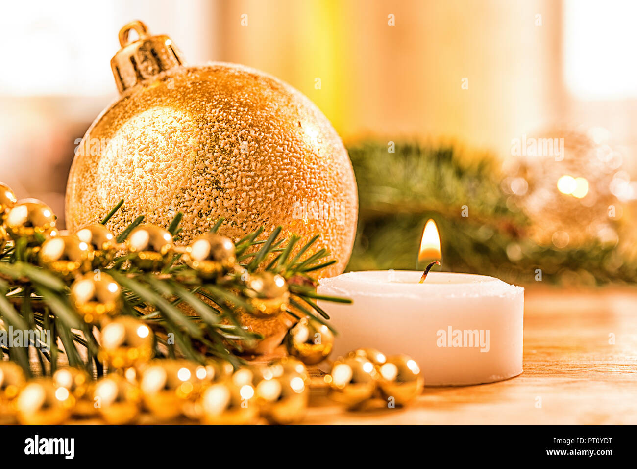 Goldene christbaumkugel mit Tannenzweig, Kerze,  Lichter und Deko Stock Photo