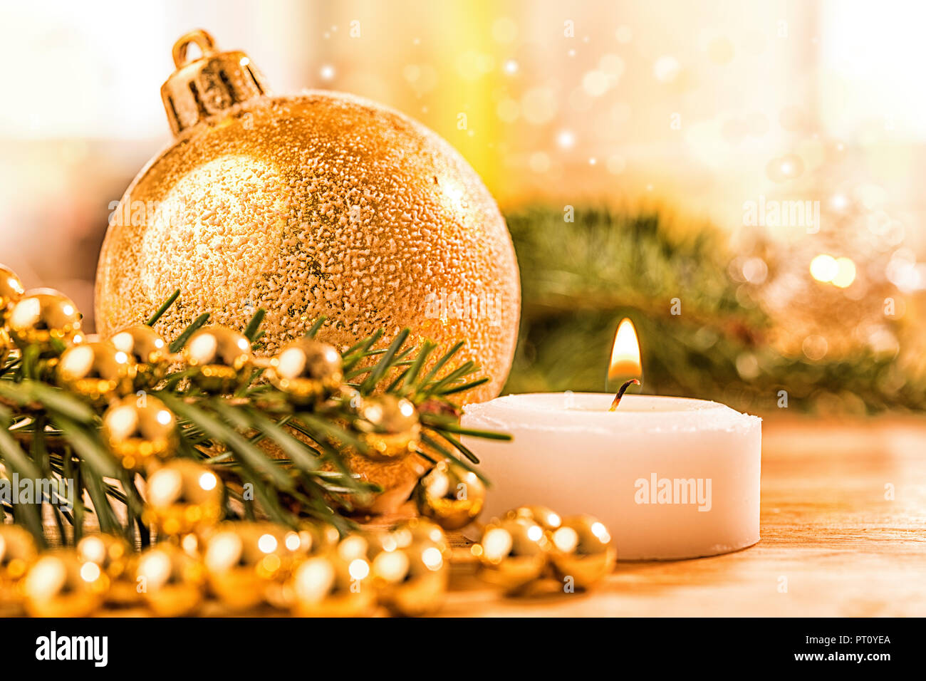 Goldene christbaumkugel mit Tannenzweig, Kerze,  Lichter und Deko Stock Photo