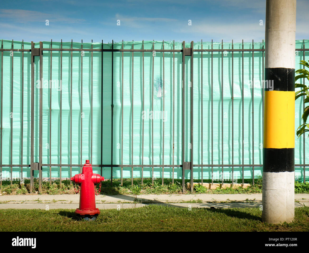 iron construction fence with a fire hydrant and a Street pole Stock Photo