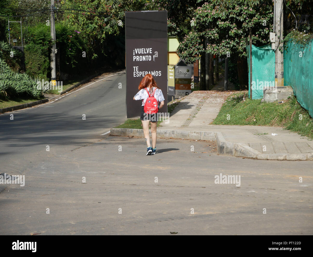 red haired girl walking away on the Street with a billboard saying come ...