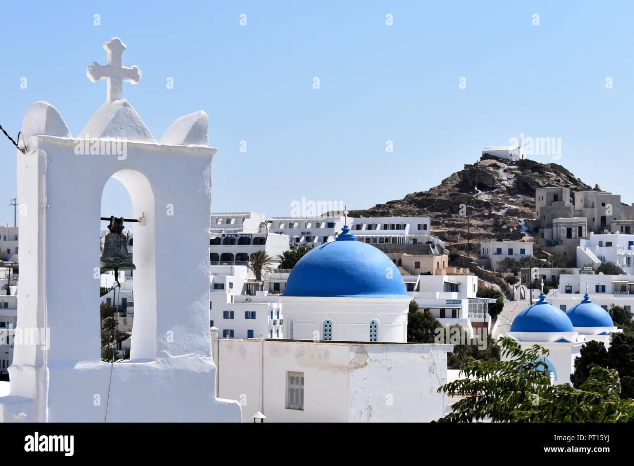 Row of churches in the old village at the beautiful Greek island of Ios. Brightly painted blue domes and a traditional white painted bell tower. Stock Photo