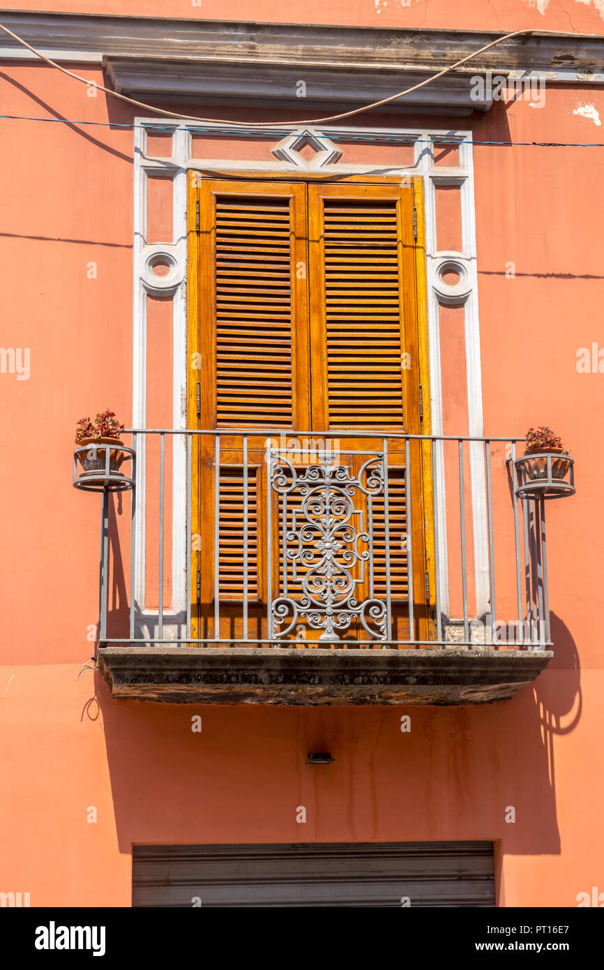 Traditional Italian door with shutters, metal balcony Italy, orange brown wall over shop, old fashioned concept, ornate,  wooden shutter doors Stock Photo