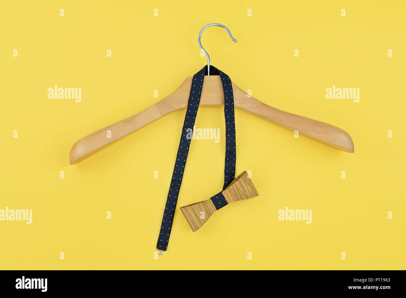Pre-tied bow hanged into wooden hanger on yellow background. Preparing for party, date, corporate dinner concept Stock Photo