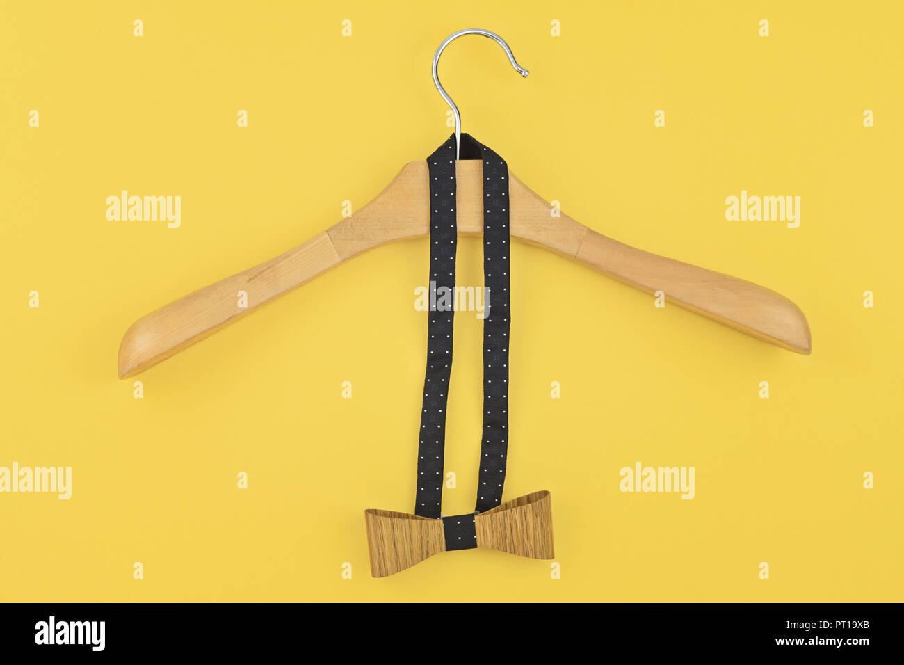 Pre-tied bow hanged into wooden hanger on yellow background. Preparing for party, date, corporate Christmas dinner concept Stock Photo
