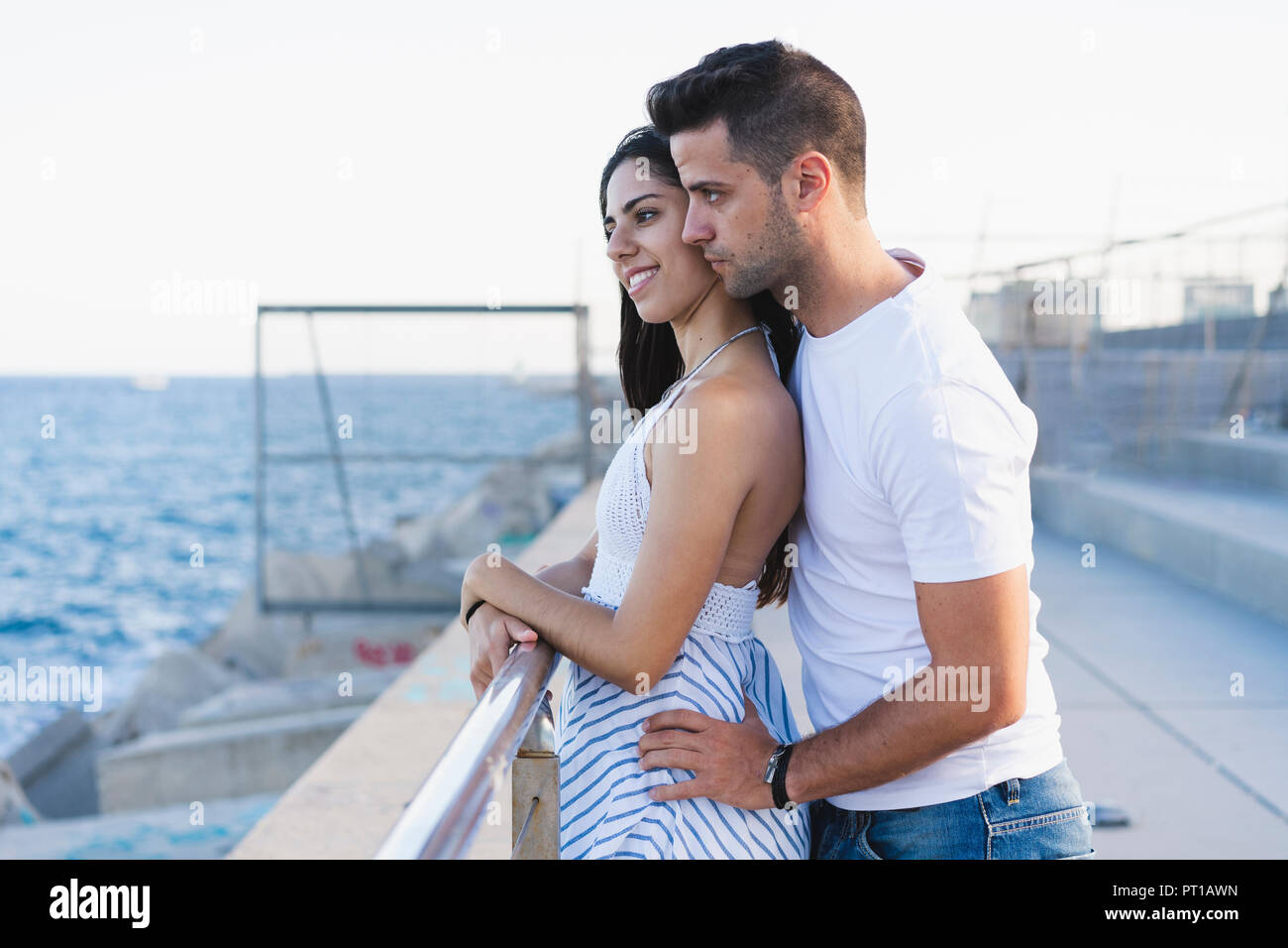 Happy young couple standing by the sea Stock Photo - Alamy