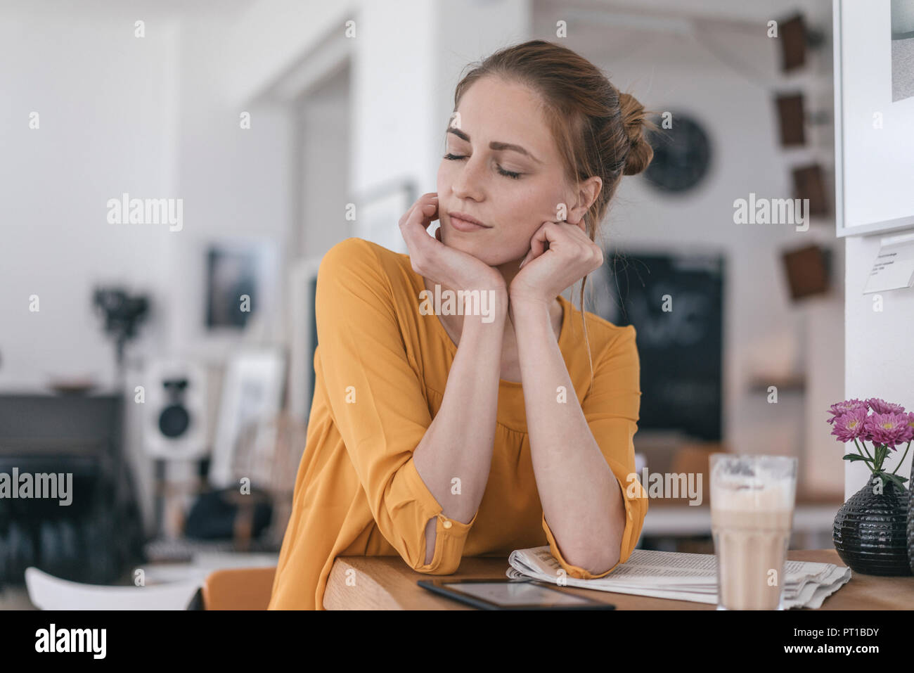 Young woman working in coworking space, closing eyes Stock Photo