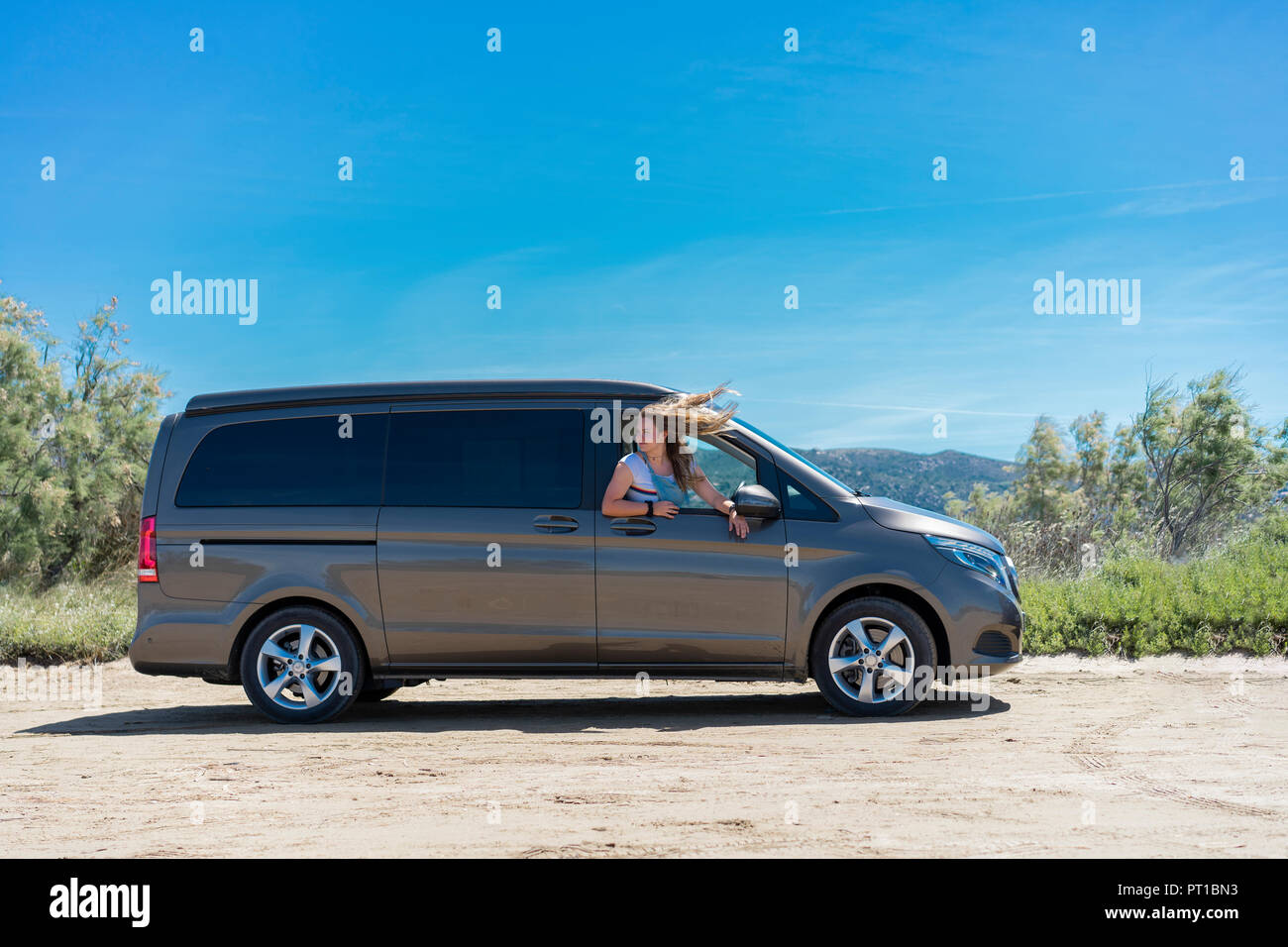 Happy woman leaning out of car window on a road trip Stock Photo - Alamy