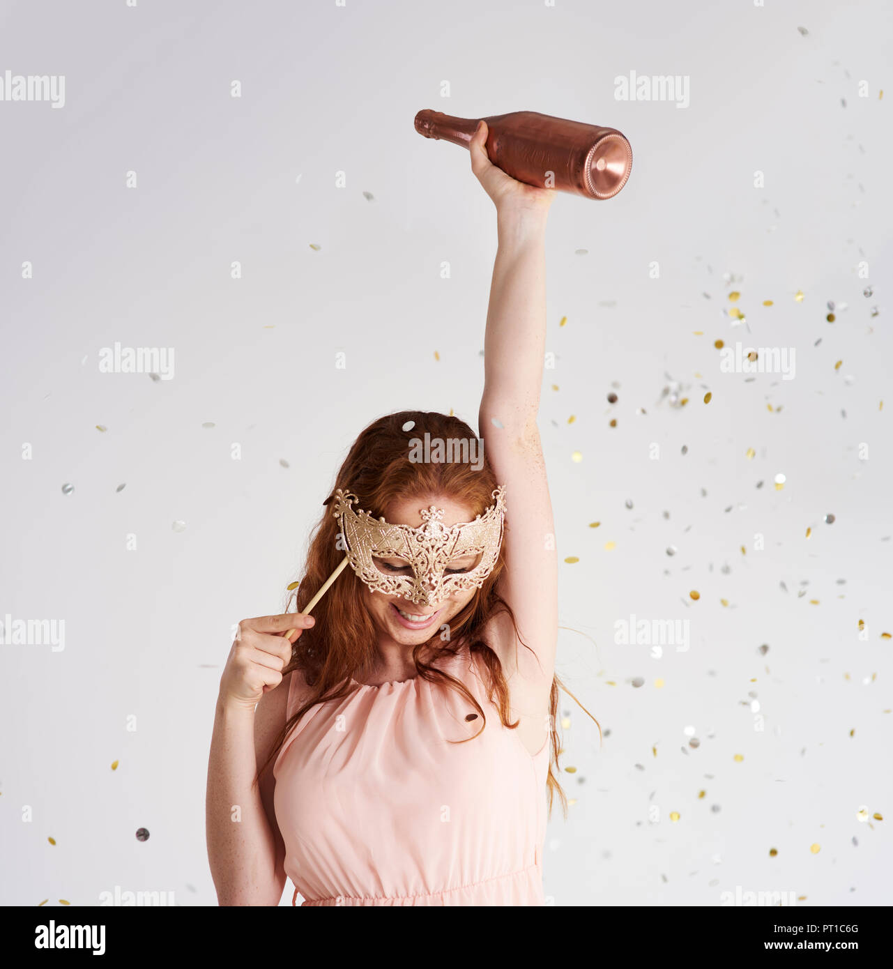 Happy young woman with bottle of champagne and masquerade mask Stock Photo