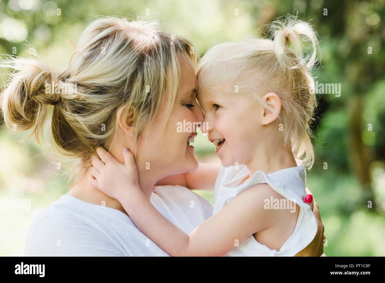Happy mother cuddling her daughter in nature Stock Photo
