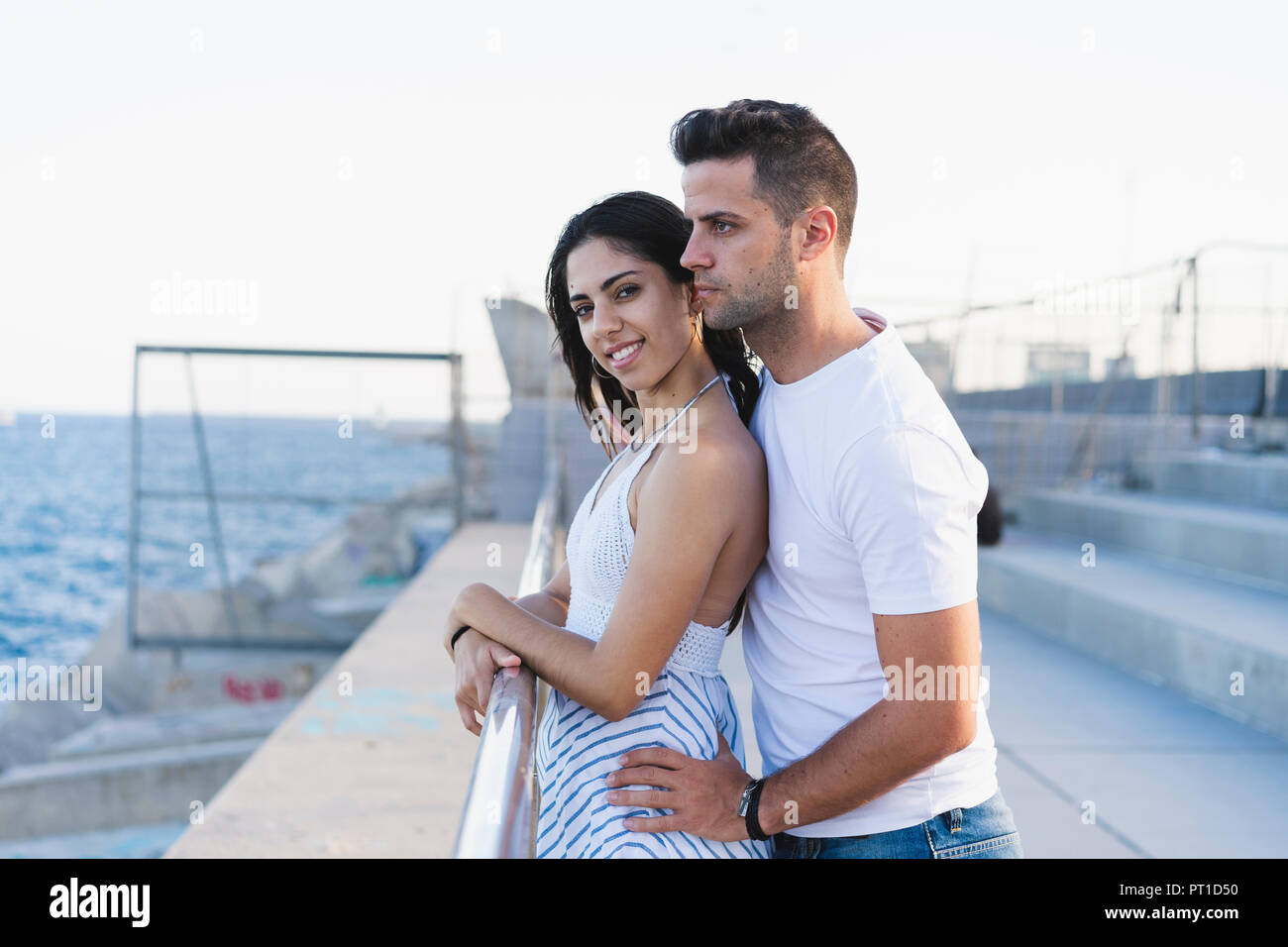 Happy young couple standing by the sea Stock Photo - Alamy