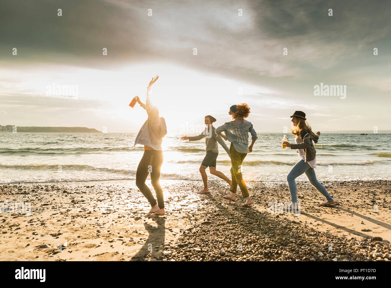 Happy friends walking on the beach at sunset Stock Photo
