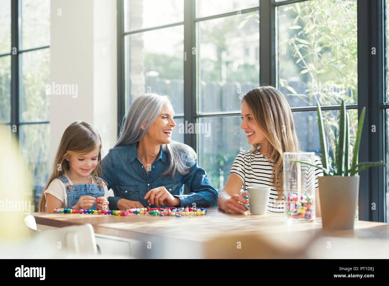 Grandmother and granddaughter and mother threading beads Stock Photo