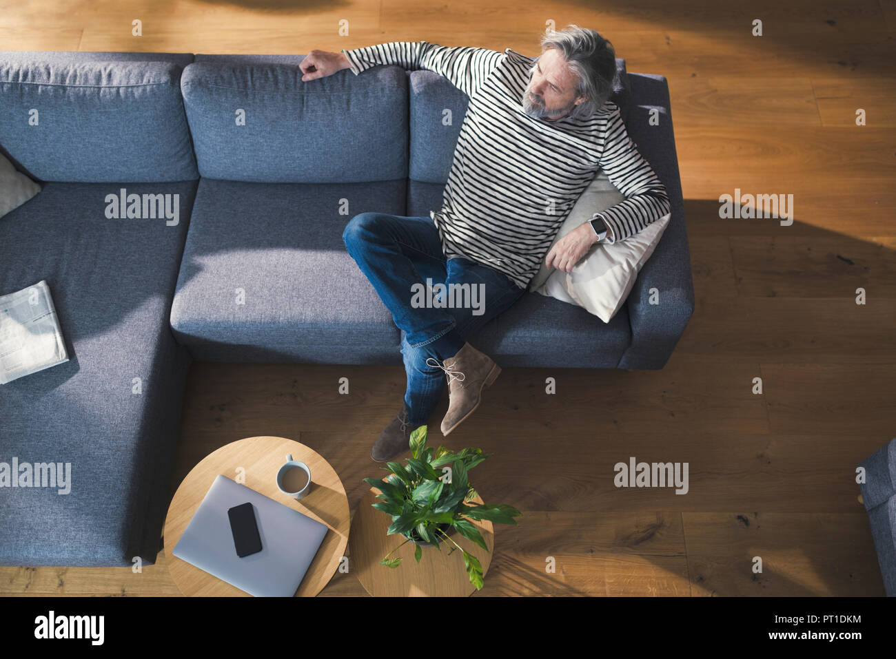 Senior man sitting on couch, relaxing and thinking Stock Photo