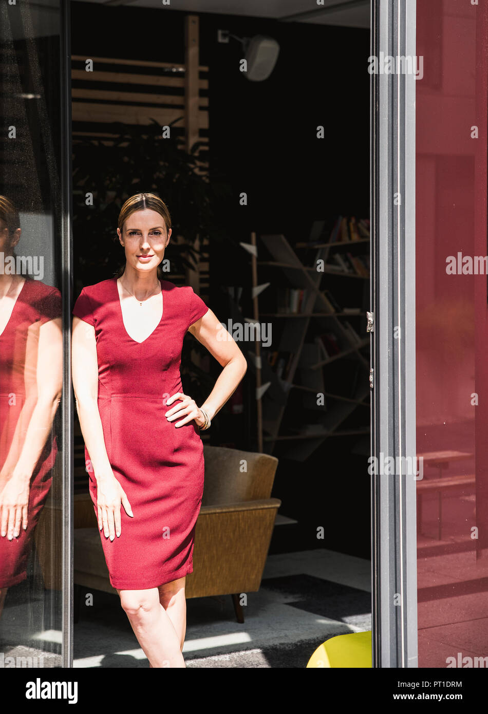 Woman wearing burgundy dress standing at the window in sunshine Stock ...
