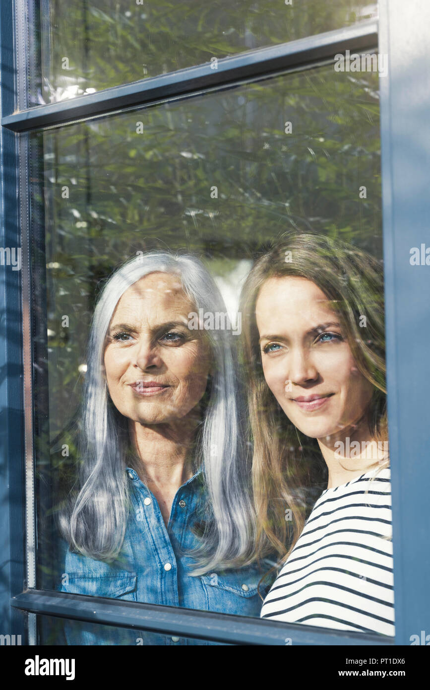 Mother and daughter looking out of window Stock Photo